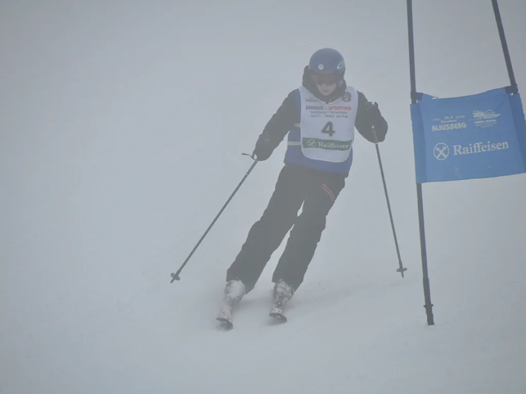 Skifahrer mit Startnummer 4 fährt durch das Tor.